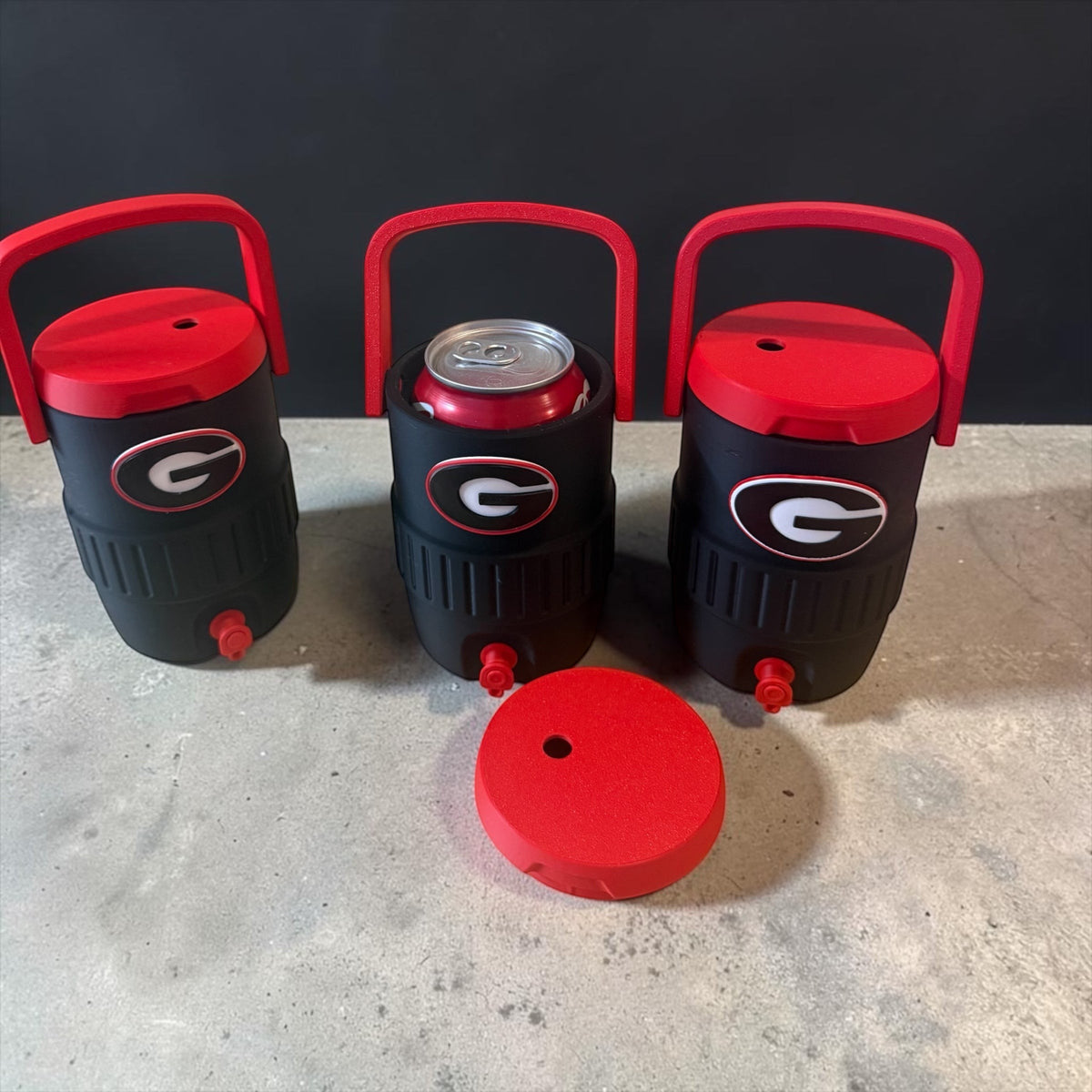 Evy's Design 12 oz can coolers in black, red, and white with Georgia Bulldogs logo. One cooler holds a can.