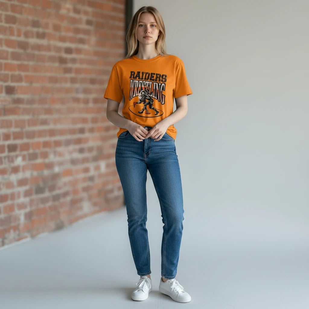 Evy's Design Habersham Raiders Wrestling t-shirt in orange with graphic print. Model wears jeans and sneakers.